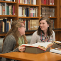 two students talking in a library
