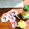 Question mark, magnifying glass and keyboard on office desk.