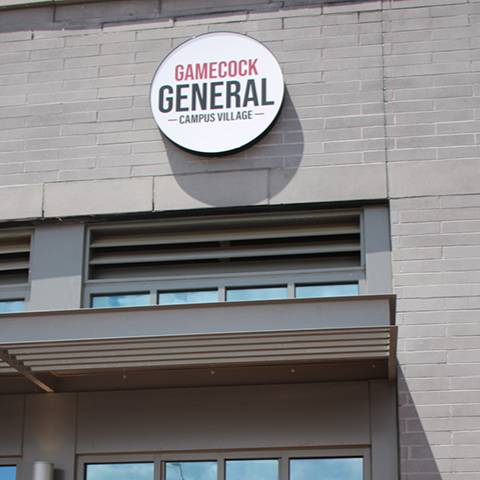 Exterior of Gamecock General at Campus Village, featuring the store’s round sign above the entrance.