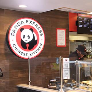 Panda Express Chinese Kitchen counter with the panda logo, menu boards, food service area, and an employee behind the counter.