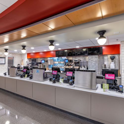 Chick-fil-A service counter with ordering registers, stainless steel equipment, and an open kitchen area.