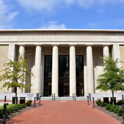 Exterior of law building with stone pillars and red brick walkway
