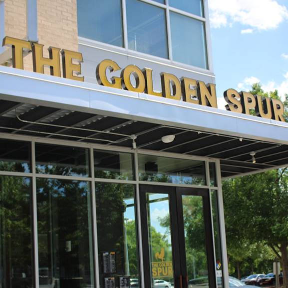 Exterior entrance of The Golden Spur restaurant with large gold lettering above glass doors and windows.