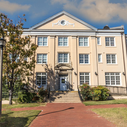 Front view of a beautifully maintained residence hall featuring classic architecture, mature landscaping, and a prominent central entrance.