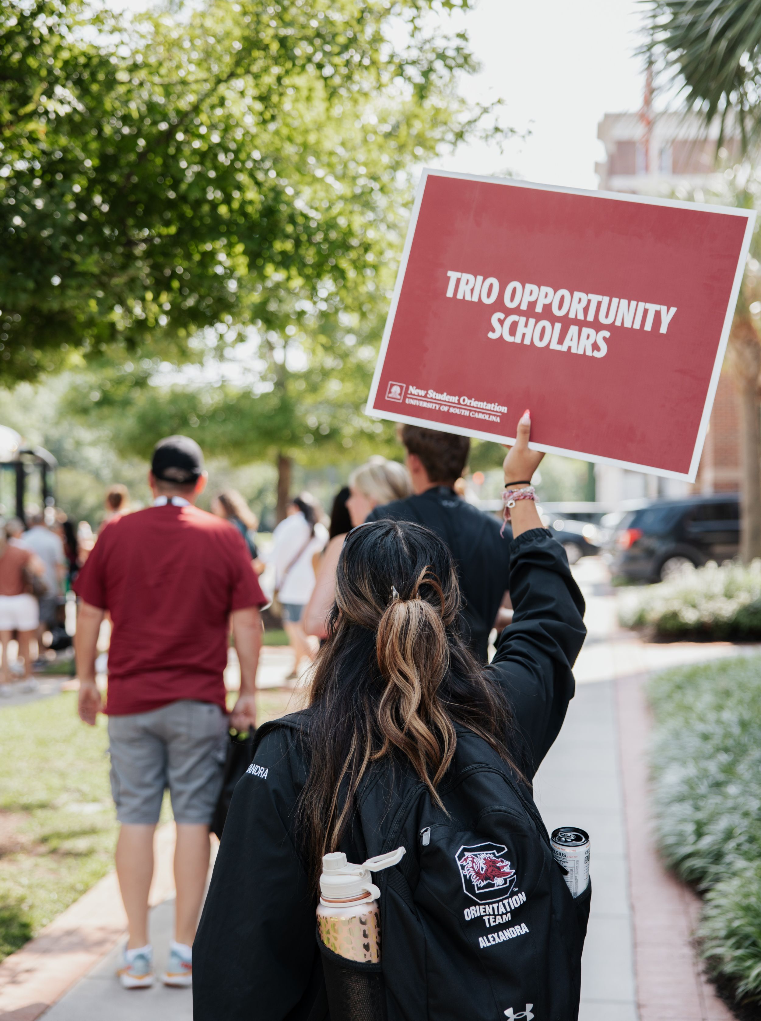 Orientation leader holding a sign that says trio opportunity scholars.