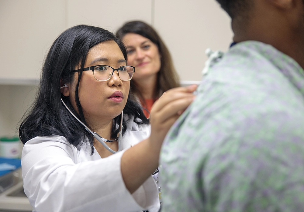 Medical student uses a stethoscope to examine a patient during a clinical training session