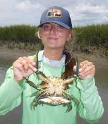 Braddock Rhodenhiser profile image. Braddock on a boat in a marsh creek holding a blue crab.