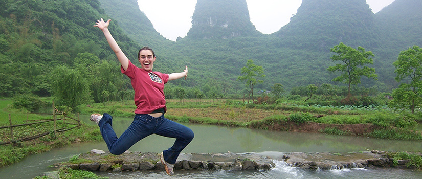 Student leaping triumphantly in the mountains.