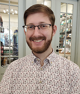 Headshot of Andrew Cerise standing outside wearing a blue plaid shirt.