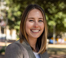 a photo of a woman wearin ga gray suit jacket smiling otuside