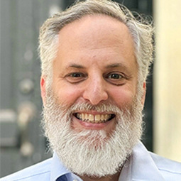 photo of a man with a beard and blue shirt on smiling