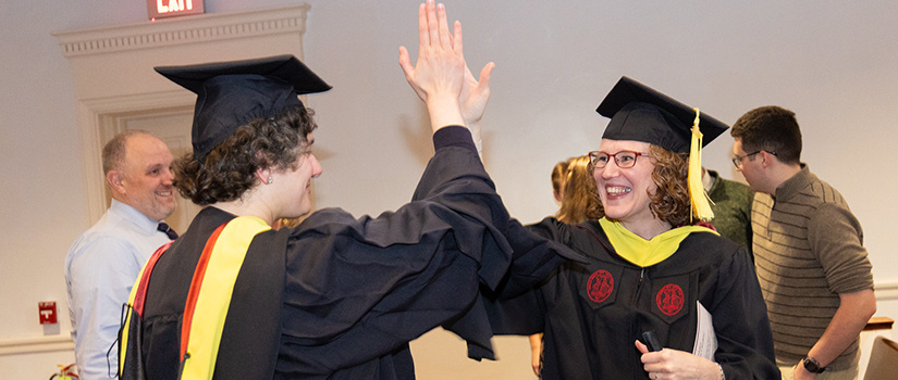 two graduates giving high fives