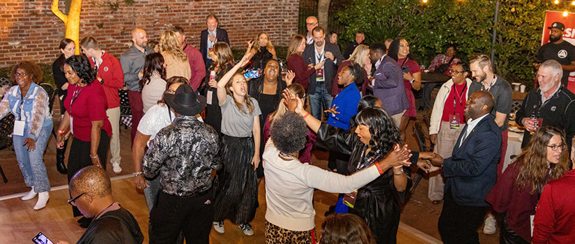 Attendees dance on an outdoor dance floor under string lights during HRSM’s Homecoming celebration.