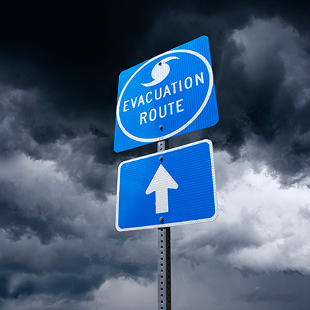 A Hurricane Evacuation Road Sign in front of dramatic storm clouds. Evacuation routes are established to guide people as they flee an area from an approaching storm. Hurricane season is usually during the months of September and October. However, with global warming, major storms are developing earlier in the year. Wide angle, panoramic view can be used for web and billboard applications.