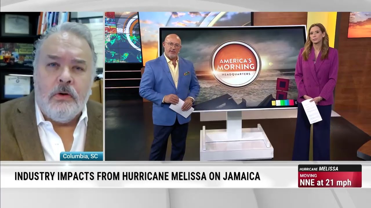 A television news segment shows a split-screen broadcast. On the left, a man in a brown blazer and white shirt speaks remotely from Columbia, South Carolina. On the right, two anchors stand in a studio with a large screen displaying the “America’s Morning Headquarters” logo and storm graphics. The on-screen text reads: “Industry impacts from Hurricane Melissa on Jamaica,” with a storm tracker indicating Hurricane Melissa moving north-northeast at 21 mph.