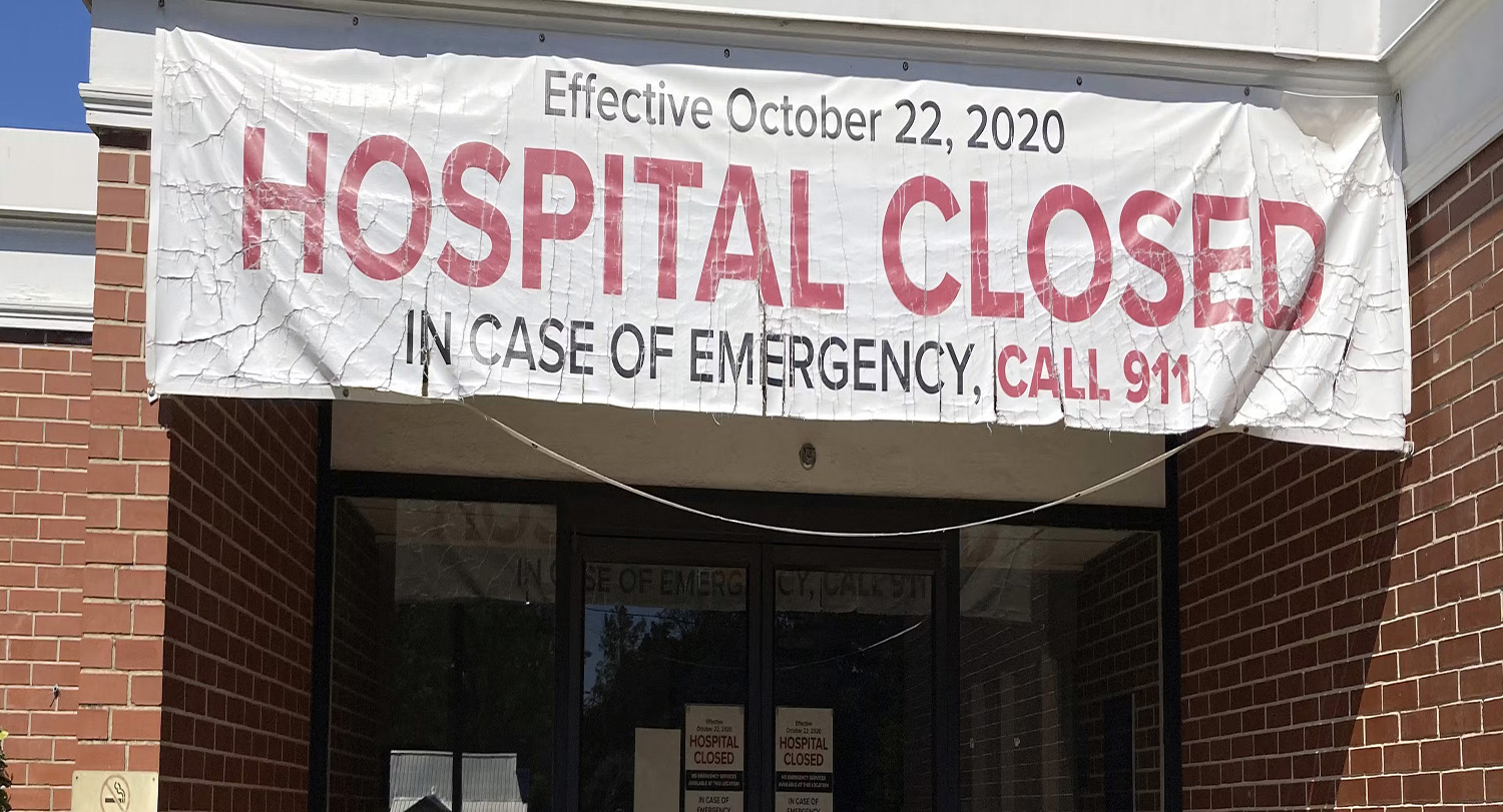 A banner hangs outside a building with the message 'HOSPITAL CLOSED'