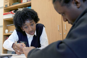 two people sit at a table looking at papers