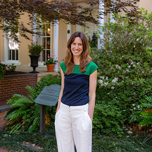 a woman standing in front of greenery