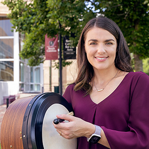Woman on campus holding a drum