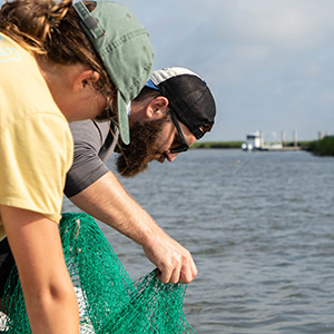 Researchers lower nets into coastal waters.