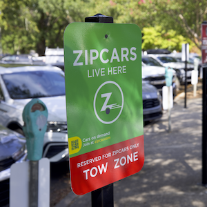 parking sign that reads zipcars live here, cards on demend, reserved for zipcars only tow zone