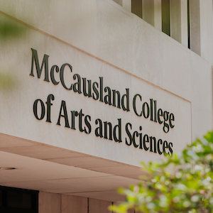 beige building with black 'McCausland College of Arts and Sciences' on the facade