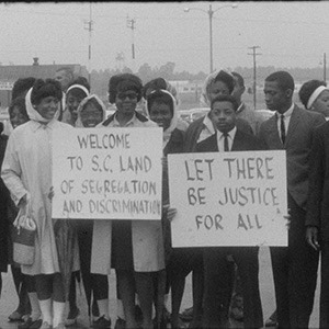 Civil rights protesters stand with signs reading 'Let there be justice for all.'