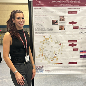 Katherine Palmer stands next to her poster titled 'Audio Equalization of Misophonia Stimuli.' Remaining poster text is not distinguishable.