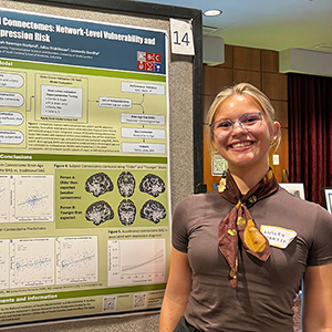 Ansley Martin stands next to her poster titled 'Brain Age Estimation from Structural Outcomes: Network-Level Vulnerability and Depression Risk.' Remaining poster text is not distinguishable.