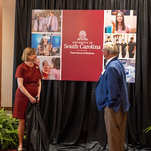Two people unveil a sign reading South Carolina Floyd School of Medicine