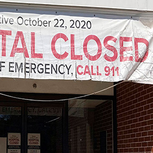 A banner hangs outside a building with the message 'HOSPITAL CLOSED'